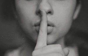 Fotografía chica con el dedo en los labios con gesto de silencio